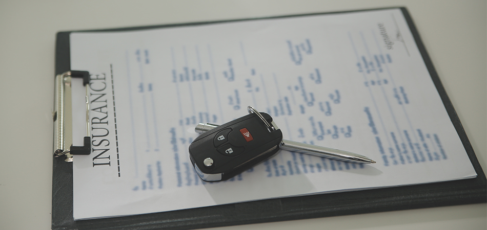 Insurance paper on a clipboard with the car keys on top of it