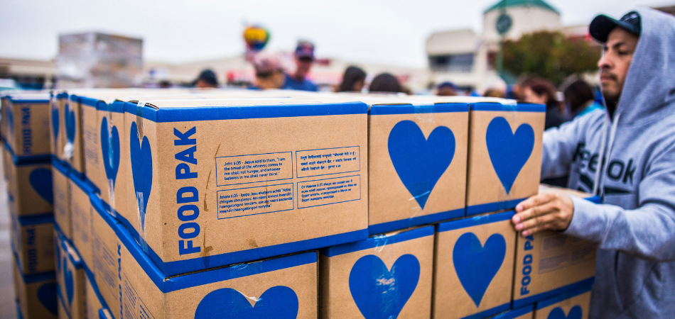 A person donating boxes of food pak to others